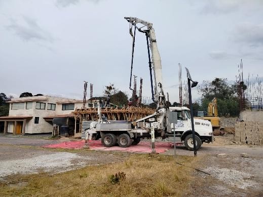Camión con bomba de concreto y brazo desplegado durante una obra residencial